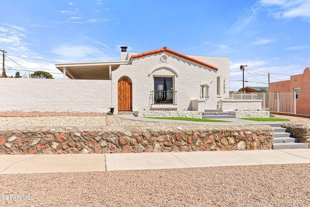 mediterranean / spanish-style home featuring fence, a chimney, and stucco siding