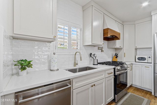 kitchen with a sink, custom exhaust hood, white cabinets, and stainless steel appliances