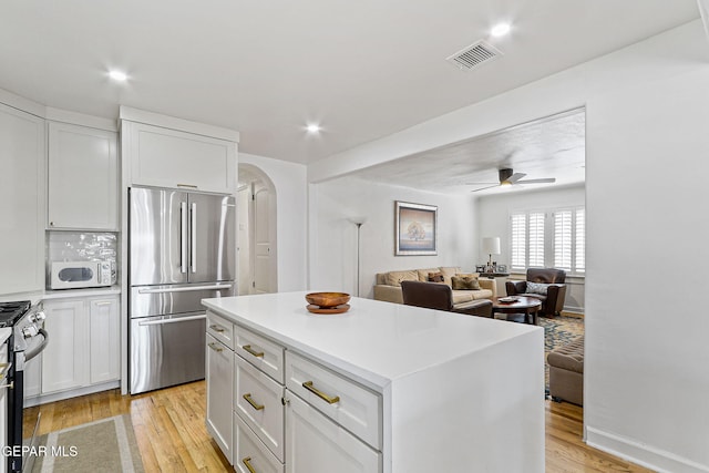 kitchen featuring visible vents, ceiling fan, white cabinets, light wood finished floors, and appliances with stainless steel finishes