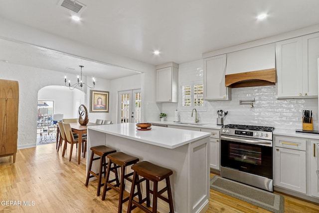 kitchen with a sink, stainless steel gas range, tasteful backsplash, and visible vents
