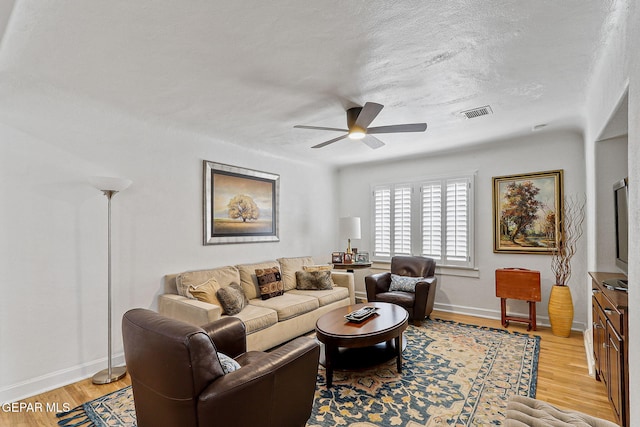 living room featuring a ceiling fan, baseboards, visible vents, and light wood-style flooring