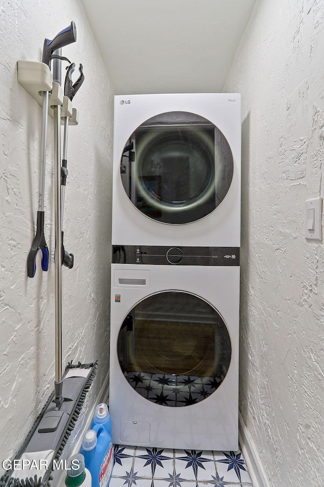 washroom featuring stacked washing maching and dryer, a textured wall, and laundry area