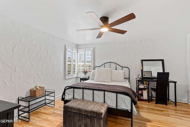bedroom featuring ceiling fan, a textured wall, and wood finished floors