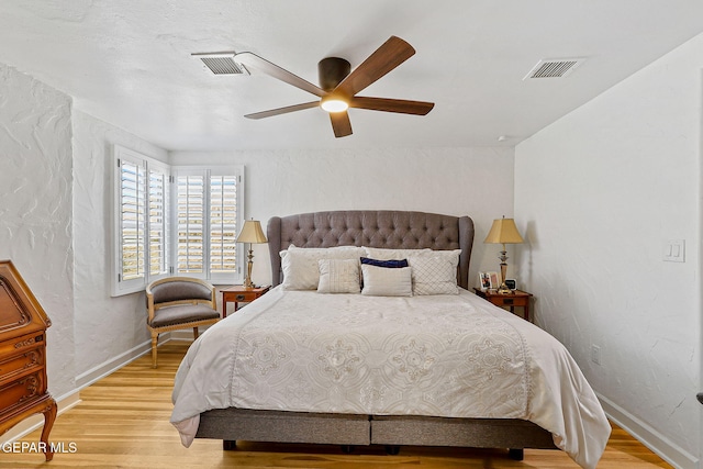 bedroom with baseboards, visible vents, and wood finished floors