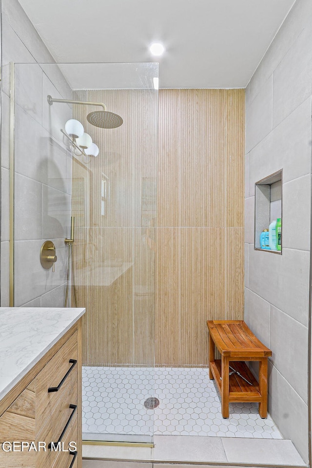 bathroom featuring tile walls, tiled shower, and vanity