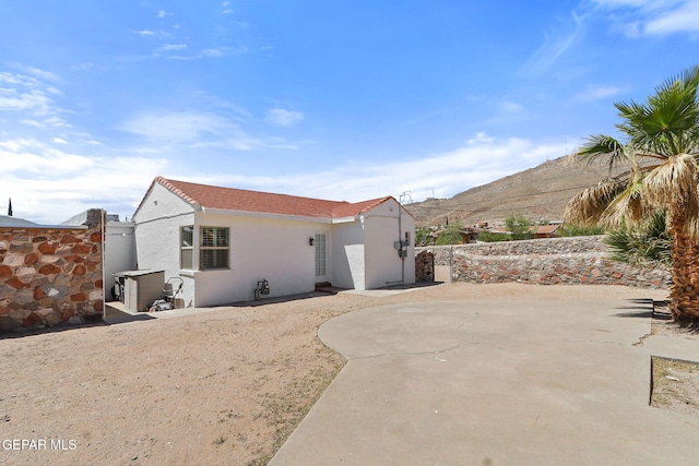 rear view of property featuring a patio area, a mountain view, stucco siding, and fence