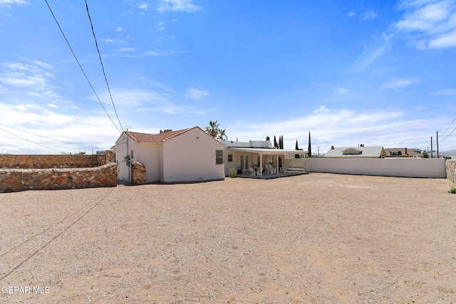 rear view of house with a patio, fence, and stucco siding
