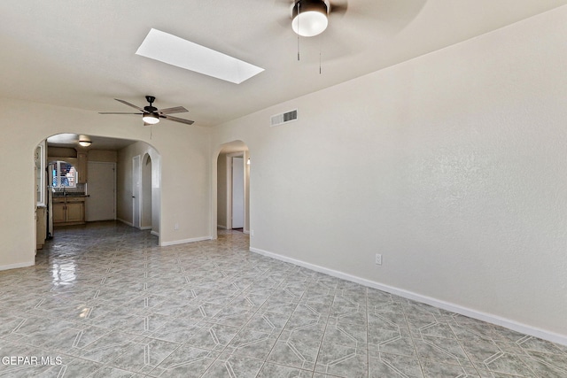 spare room with ceiling fan, baseboards, visible vents, and arched walkways