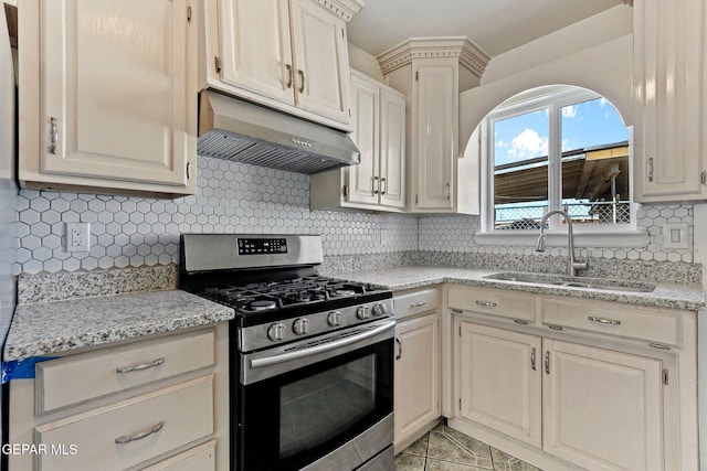 kitchen featuring stainless steel range with gas cooktop, light stone counters, decorative backsplash, a sink, and under cabinet range hood