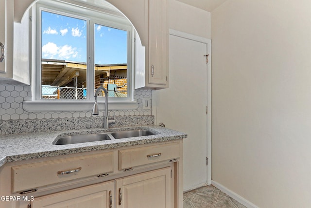 kitchen with baseboards, a wealth of natural light, backsplash, and a sink