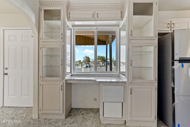 kitchen with arched walkways, light tile patterned flooring, and freestanding refrigerator