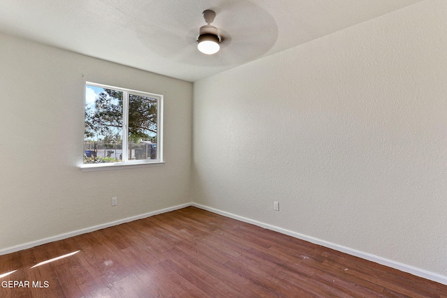 spare room featuring baseboards, wood finished floors, and ceiling fan