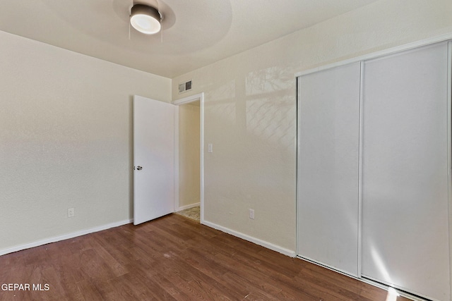 unfurnished bedroom with wood finished floors, a closet, baseboards, visible vents, and a ceiling fan