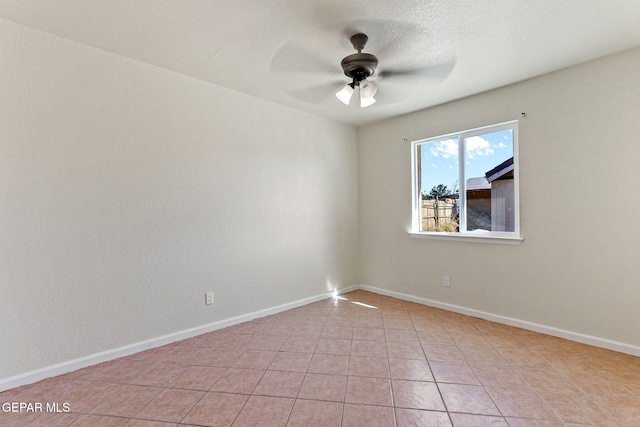 spare room with light tile patterned floors, ceiling fan, and baseboards
