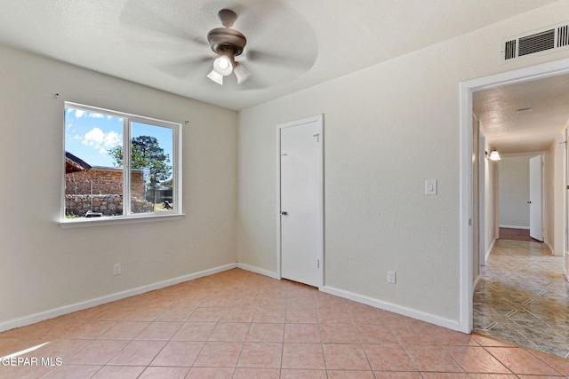 unfurnished room with baseboards, visible vents, light tile patterned floors, and ceiling fan