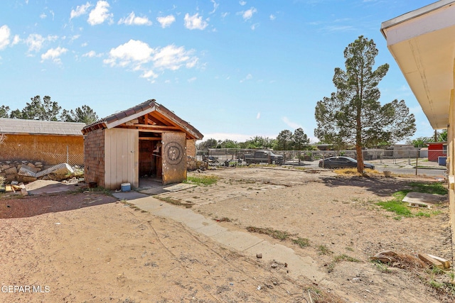 view of yard featuring a storage unit, fence, and an outbuilding