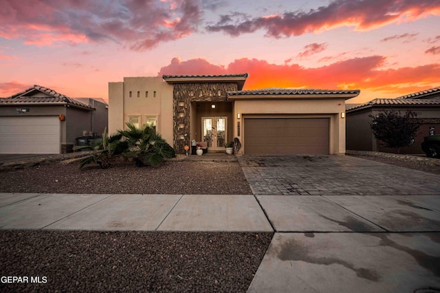 mediterranean / spanish-style house featuring a tiled roof, stucco siding, an attached garage, driveway, and french doors