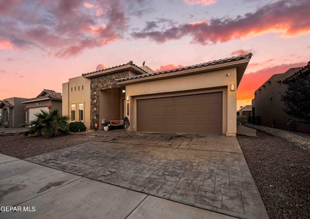 mediterranean / spanish-style home with stucco siding, an attached garage, decorative driveway, and a tile roof