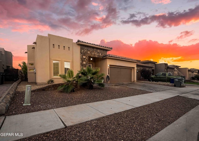 view of front facade featuring concrete driveway, a garage, a tiled roof, and stucco siding