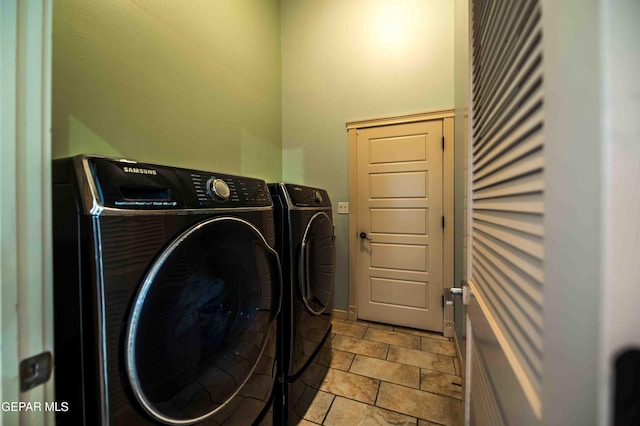 washroom with stone finish floor, washing machine and clothes dryer, and laundry area