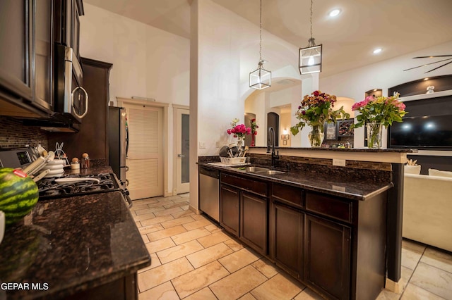 kitchen with dark brown cabinetry, stainless steel appliances, arched walkways, and a sink
