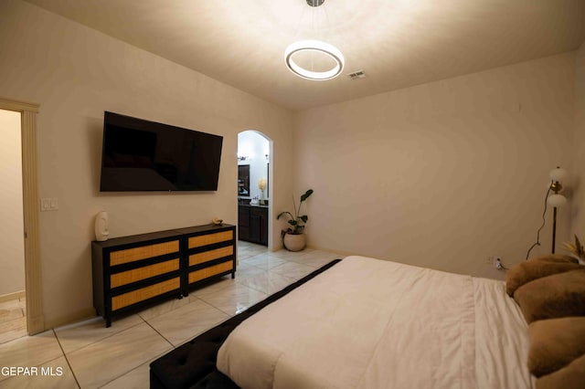 bedroom featuring baseboards, visible vents, arched walkways, and connected bathroom
