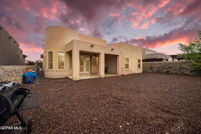 rear view of house featuring fence, a patio area, french doors, and stucco siding