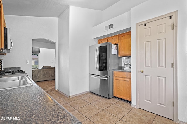 11400 Pifas Nevarez Pl, El Paso, TX 79934 - kitchen with light tile patterned floors, visible vents, arched walkways, dark countertops, and appliances with stainless steel finishes