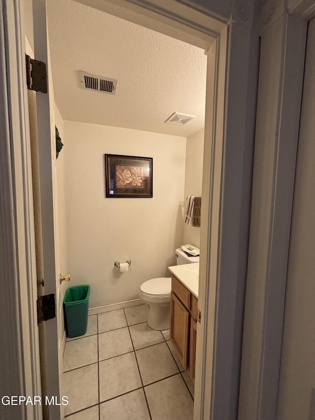 bathroom with toilet, visible vents, vanity, and tile patterned flooring