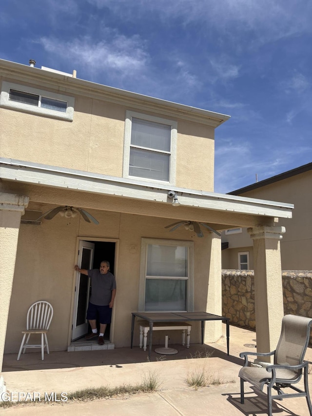 rear view of property with stucco siding, a ceiling fan, and a patio area