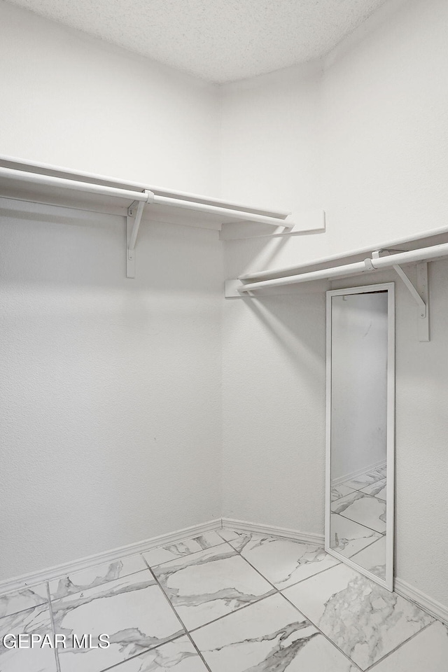 spacious closet featuring marble finish floor