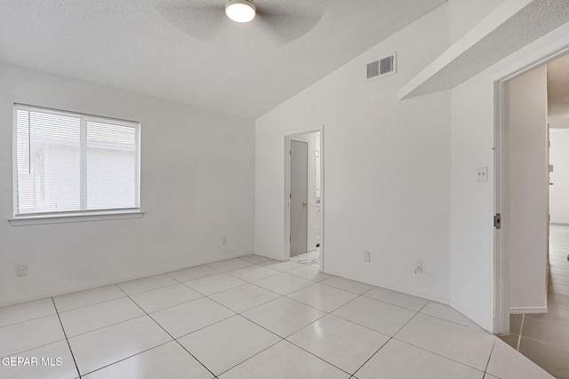 empty room with ceiling fan, visible vents, light tile patterned flooring, and vaulted ceiling