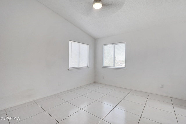 unfurnished room with a textured ceiling, vaulted ceiling, light tile patterned floors, and ceiling fan