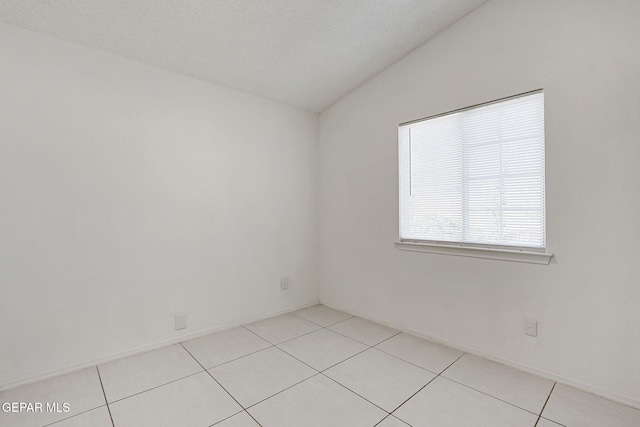 unfurnished room with lofted ceiling, baseboards, and light tile patterned floors
