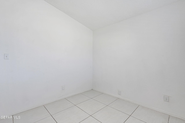 spare room with light tile patterned floors and baseboards