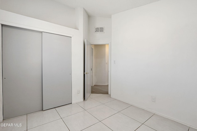 unfurnished bedroom featuring a closet, light tile patterned floors, visible vents, and baseboards