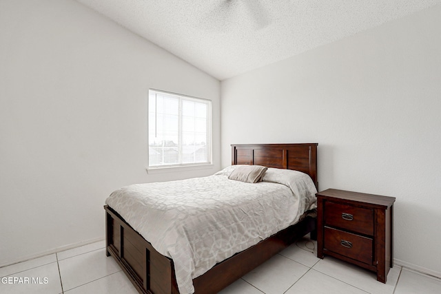 bedroom with lofted ceiling, a textured ceiling, baseboards, and light tile patterned floors
