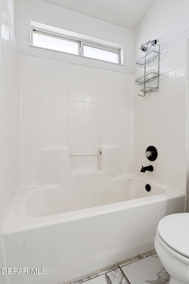 bathroom featuring toilet, marble finish floor, and bathtub / shower combination