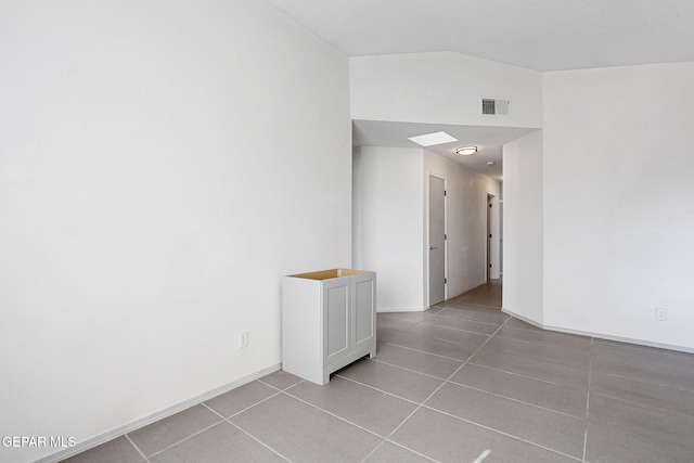 unfurnished room featuring light tile patterned floors, baseboards, visible vents, and vaulted ceiling