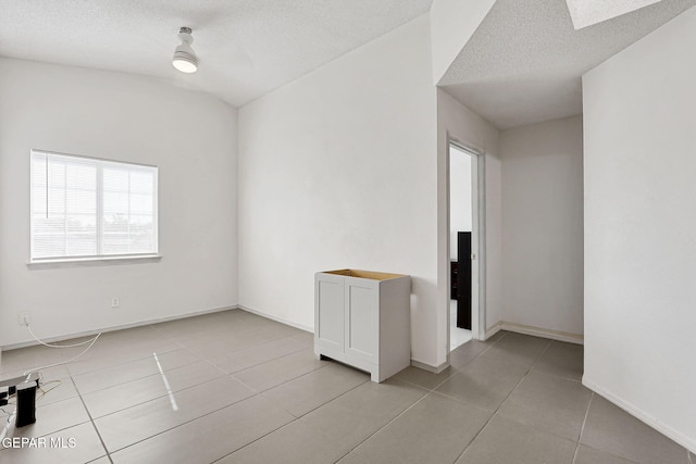 spare room featuring baseboards, light tile patterned flooring, and a textured ceiling