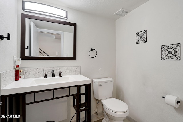half bath featuring toilet, vanity, and visible vents