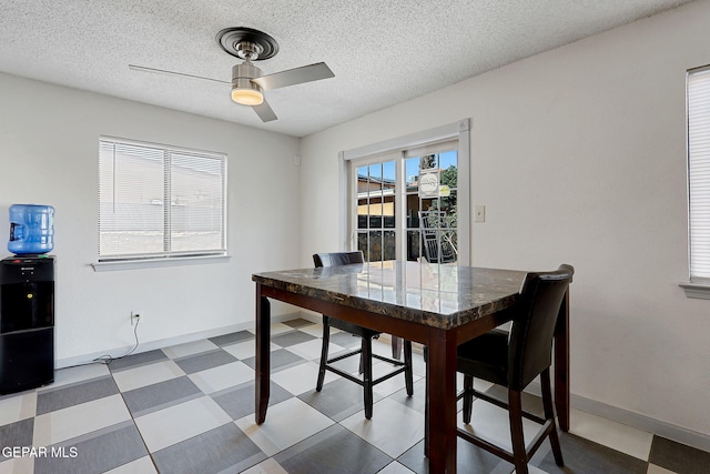 dining area with ceiling fan, a textured ceiling, baseboards, and tile patterned floors
