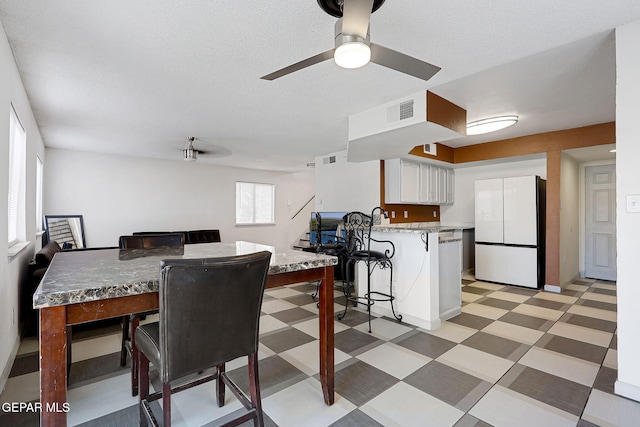dining room featuring light floors, ceiling fan, and visible vents