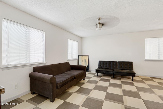 living area with ceiling fan and a textured ceiling