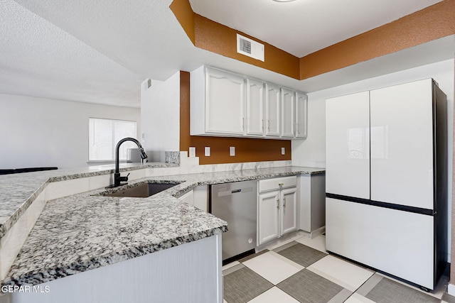 kitchen with freestanding refrigerator, white cabinetry, stainless steel dishwasher, and a sink