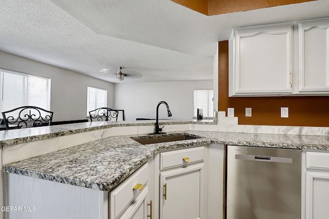 kitchen with a sink, a peninsula, a textured ceiling, dishwasher, and white cabinetry