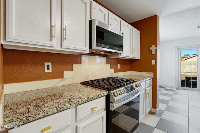 kitchen with appliances with stainless steel finishes, baseboards, light stone countertops, and white cabinetry
