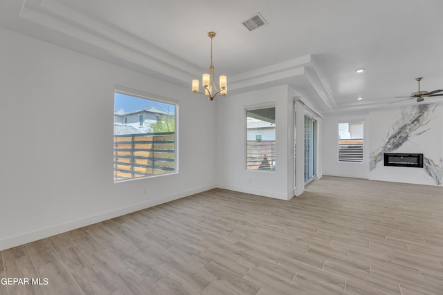 unfurnished room featuring baseboards, visible vents, light wood-style floors, a premium fireplace, and a raised ceiling