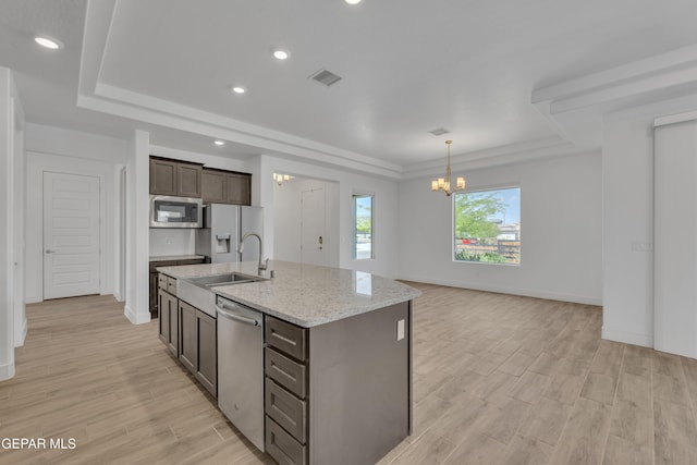 kitchen featuring a sink, a chandelier, a tray ceiling, stainless steel appliances, and visible vents