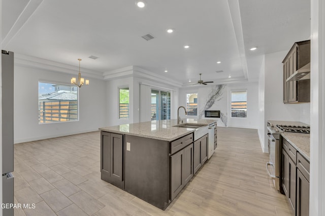 kitchen featuring visible vents, a sink, stainless steel gas range, a kitchen island with sink, and open floor plan